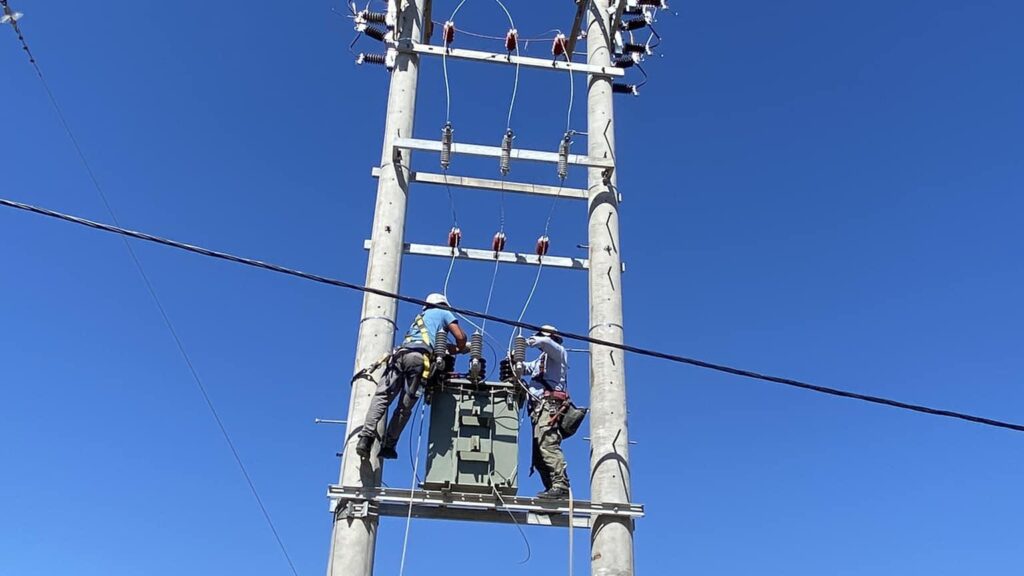 A professional lineman wearing safety gear, working on high-voltage electrical lines from a bucket truck, ensuring power system maintenance.